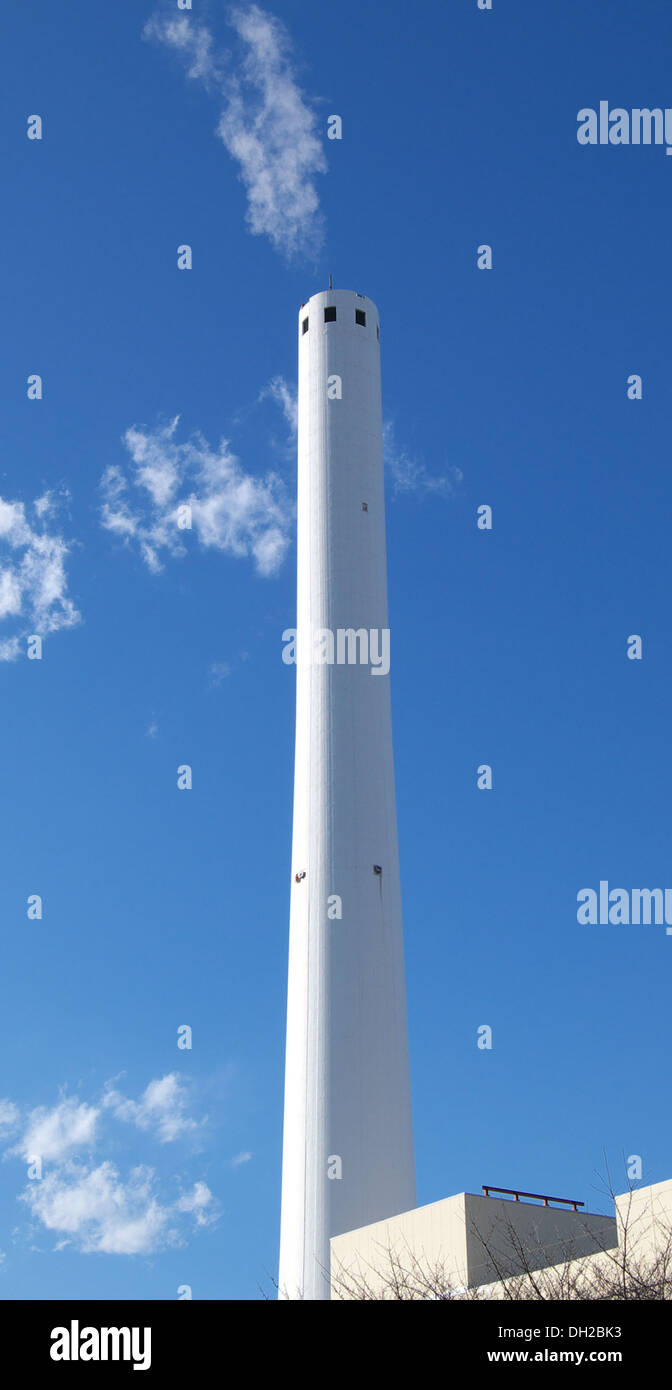 Questo camino fa parte di un impianto di incenerimento, utilizzato per bruciare materiali di scarto ad alte temperature. L'incenerimento è un processo di gestione dei rifiuti che aiuta a ridurre il volume dei rifiuti e a generare energia in alcuni sistemi. Foto Stock