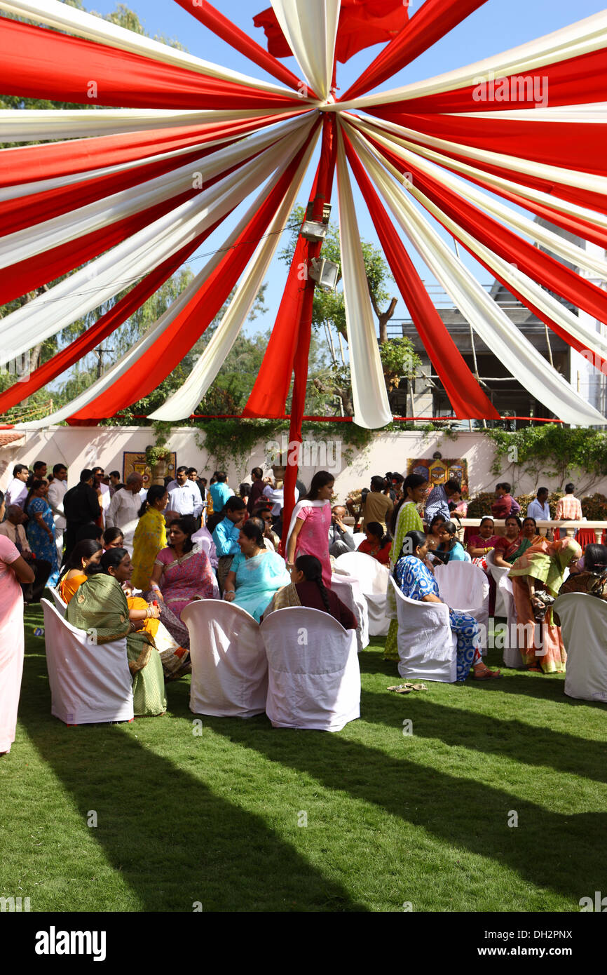 La gente seduta al di sotto di rosso bianco tessuto streamers baldacchino indiano cerimonia di nozze Jabalpur Madhya Pradesh India Asia Foto Stock