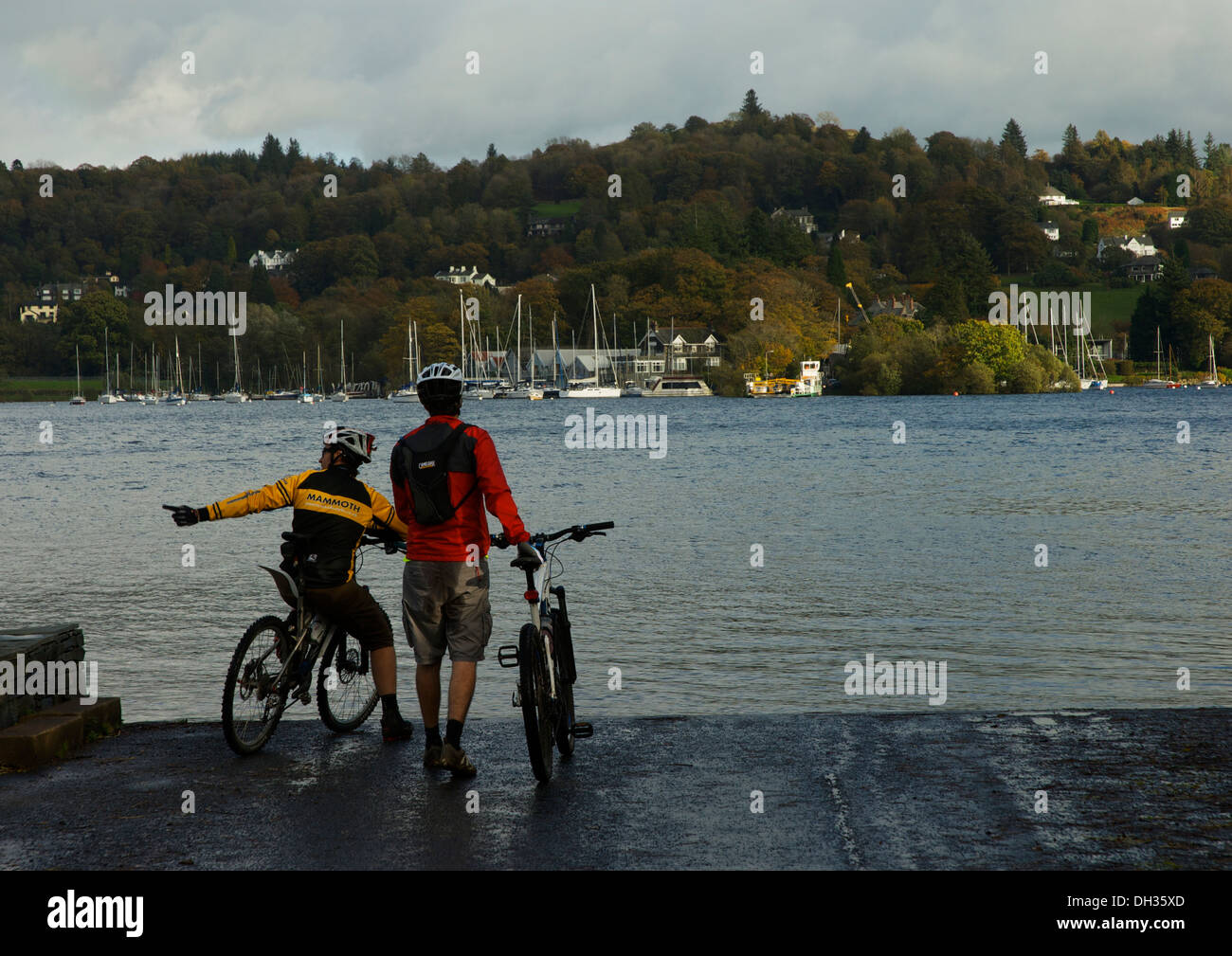 Due giovani uomini in mountain bike, aspettando il Windermere ferry, Parco Nazionale del Distretto dei Laghi, Cumbria, England Regno Unito Foto Stock