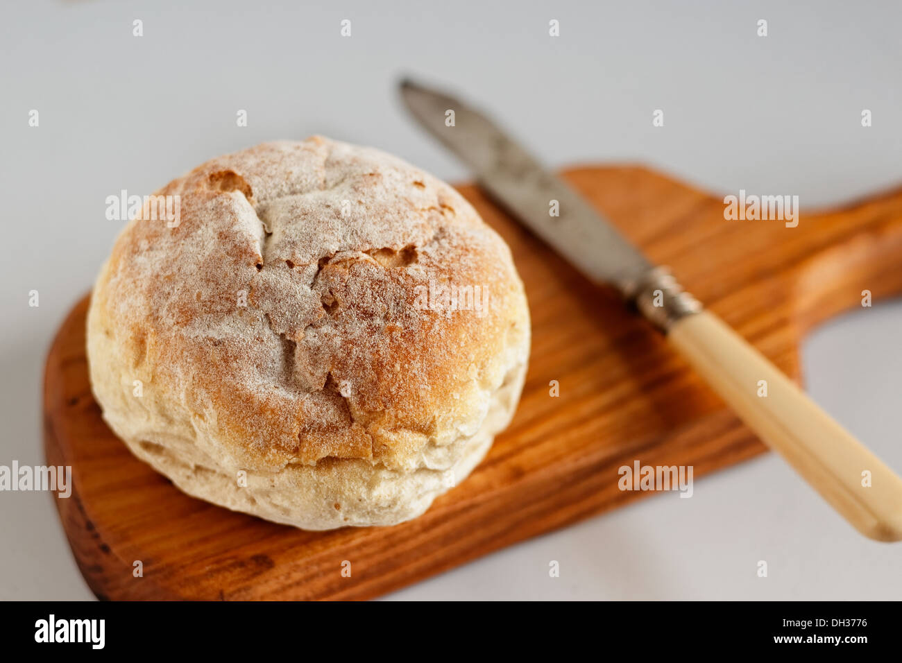 Pane fresco rotolo con coltello su una tavola di legno Foto Stock
