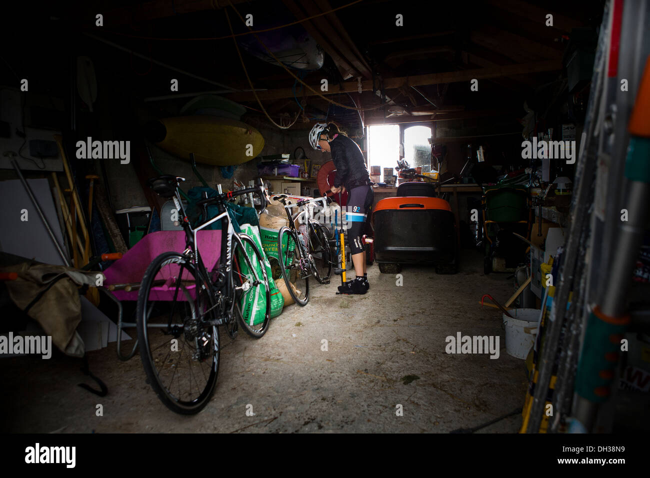 Un ciclista sorge accanto alla sua bicicletta in un garage, Highlands scozzesi, Scotland, Regno Unito Foto Stock