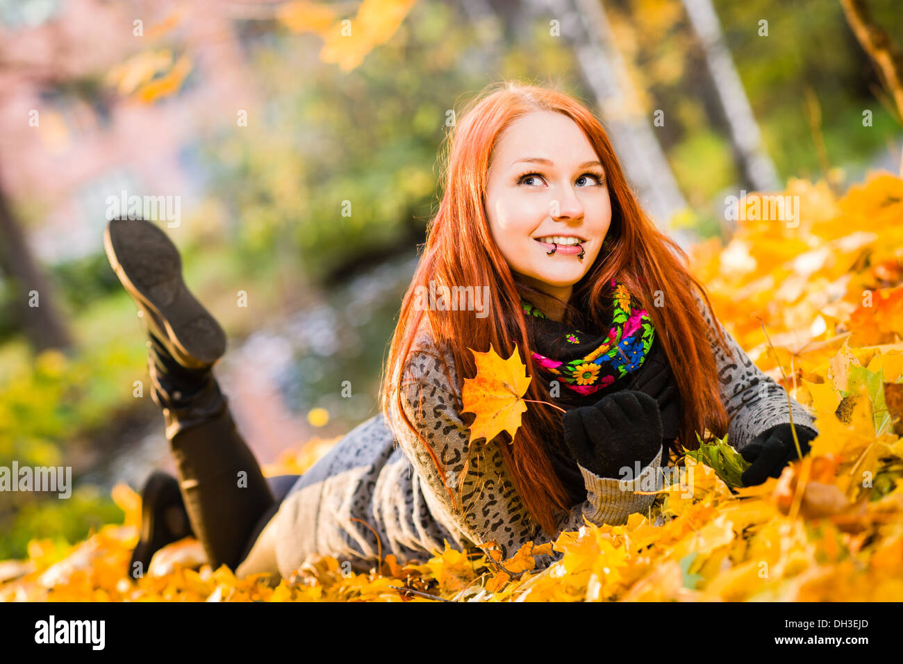 I Capelli rossi ragazza distesa sul parco, foglie di acero e colori dell'autunno Foto Stock