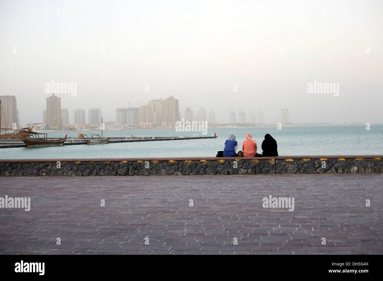 Guardando al futuro - tre donne sulla parete del mare a Katara, Doha, Qatar Foto Stock