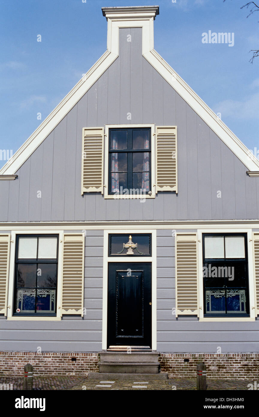 Di colore grigio pallido olandese casa clapboard con persiane bianche Foto Stock
