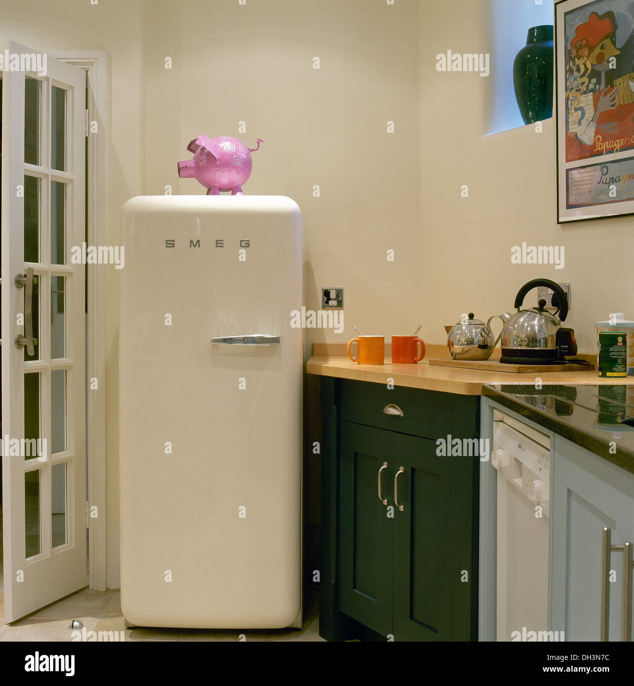 Rosa rosa in plastica su Smeg frigorifero in un angolo della cucina moderna con acciaio inox bollitore teiera sul piano di lavoro Foto Stock