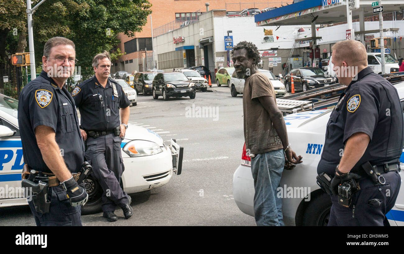3 New York gli ufficiali di polizia di trattenere mentalmente disturbato uomo in nero manette in attesa di una ambulanza a prenderlo Foto Stock