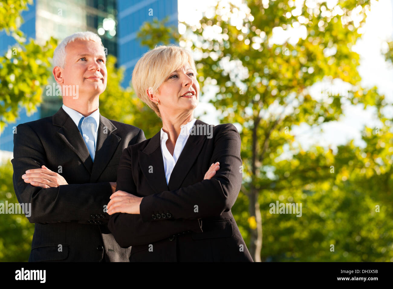 La gente di affari - maturo o senior - in piedi in un parco all'aperto di fronte ad un edificio per uffici Foto Stock