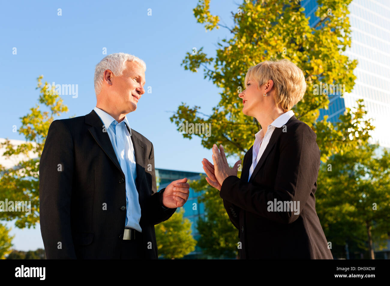 La gente di affari - maturo o senior - in piedi in un parco all'aperto a parlare Foto Stock