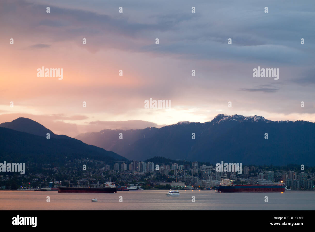 Suggestivo tramonto sopra il porto di Vancouver, North Vancouver, e Grouse Mountain come si vede dal centro cittadino di Vancouver, BC, Canada. Foto Stock