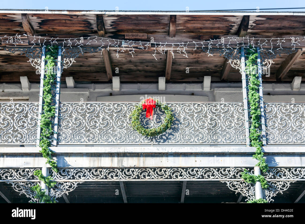 Vecchio ferro battuto ringhiera di balcone e ghirlande di Natale ghirlanda con fiocco rosso.trave di legno e asse della struttura del tetto è visibile l'acqua Foto Stock