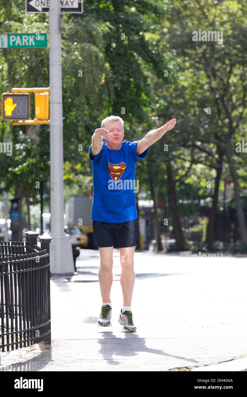 Vittorioso uomo Senior Jogging sulle strade della città indossando Superman T-Shirt, NYC Foto Stock