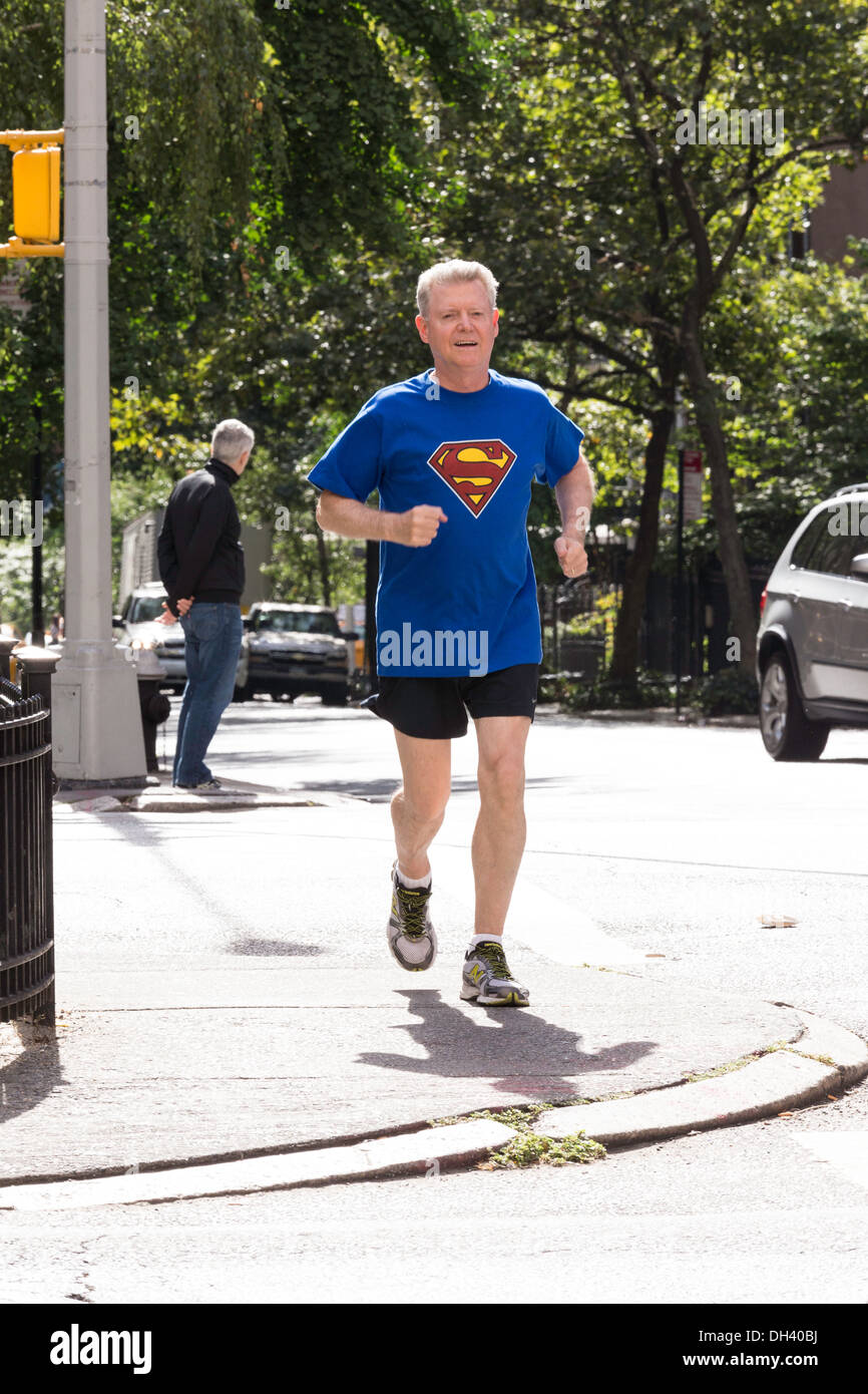 Senior uomo Fare jogging sulle strade della città indossando Superman T-Shirt, NYC Foto Stock