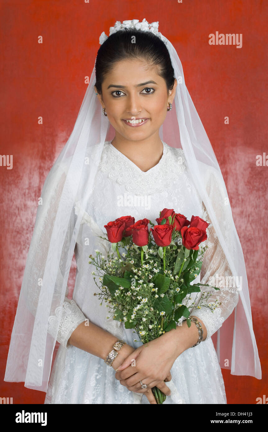 Ritratto di una sposa sposa tenendo un mazzo di fiori e sorridente Foto Stock