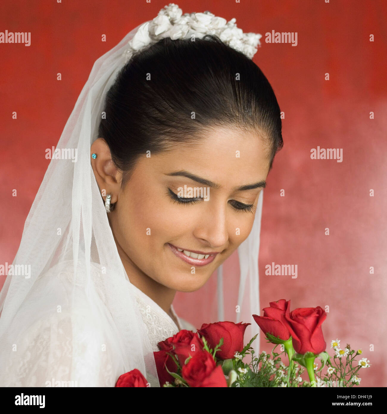 Close-up di una sposa sposa tenendo un mazzo di fiori e sorridente Foto Stock