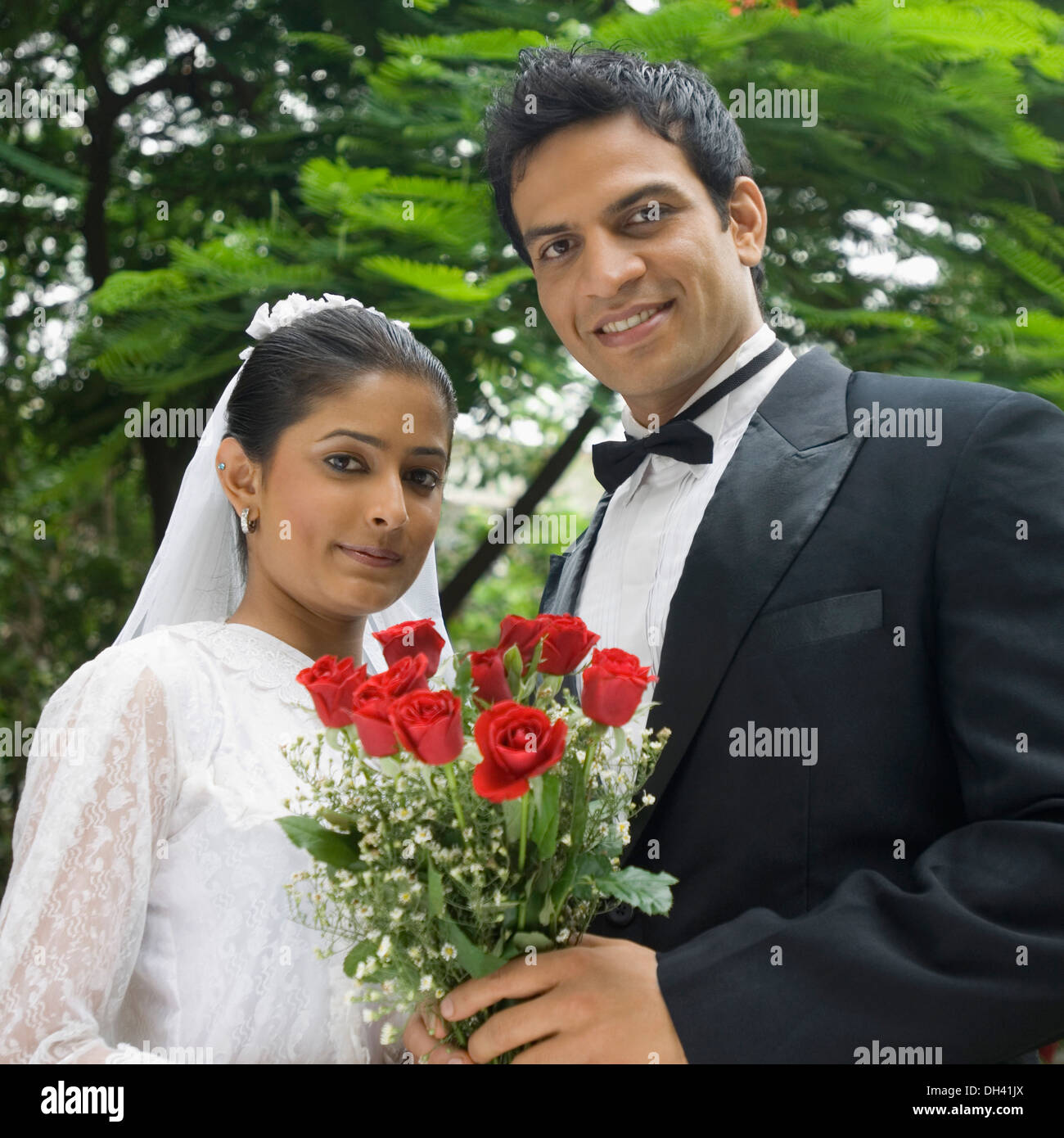 Ritratto di una sposa giovane tenendo un mazzo di fiori e sorridente Foto Stock