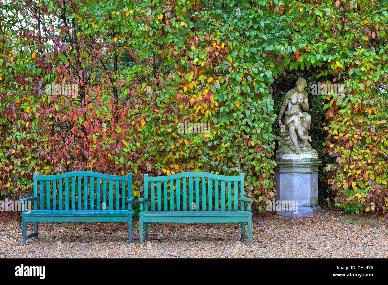 Due panche di legno sul vicolo di fronte di boccole con lussureggianti  foglie colorate e la vecchia scultura in autunno il parco di Racconigi,  Italia Foto stock - Alamy