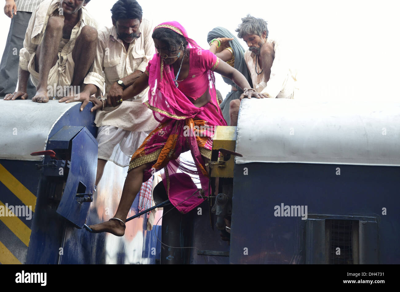 Donna indiana in piedi tra due carrozze ferroviarie vani cercando di scendere dal tetto del treno Jodhpur Rajasthan India Asia Foto Stock