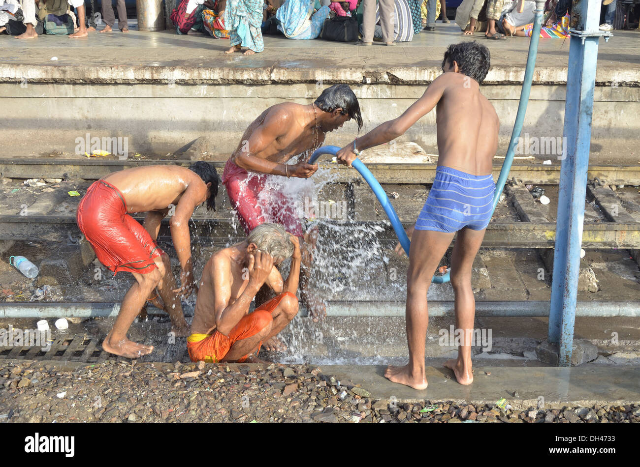 Quattro uomini di balneazione con acqua in plastica tubo sul binario ferroviario Jodhpur Rajasthan India Asia Foto Stock
