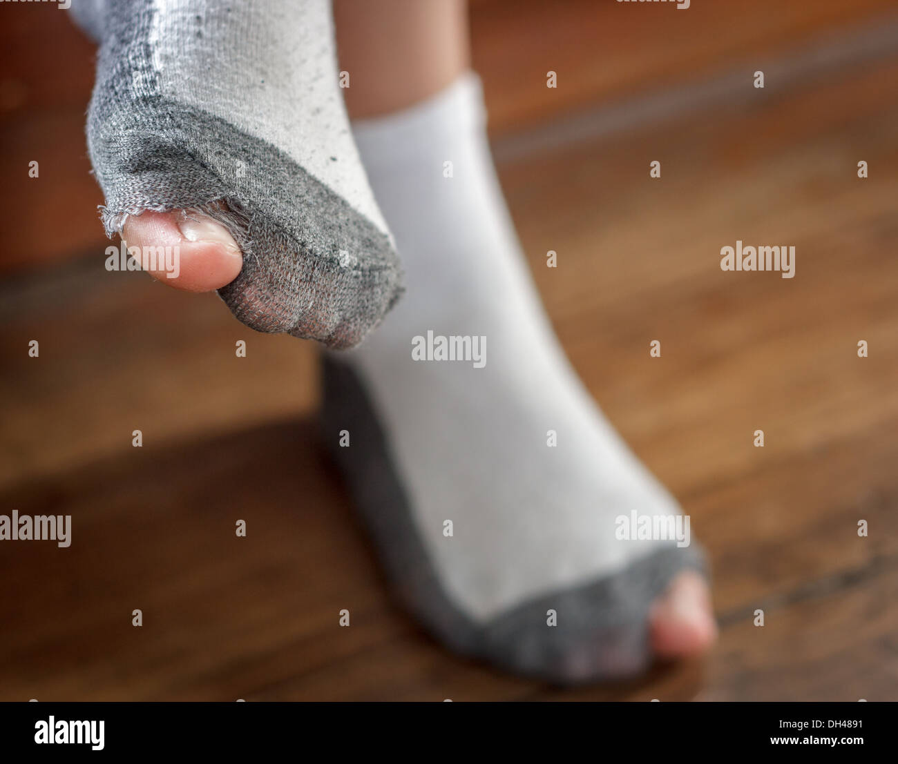 Usurati calze con un foro e le dita dei piedi spuntavano di loro sul vecchio pavimento in legno . Foto Stock