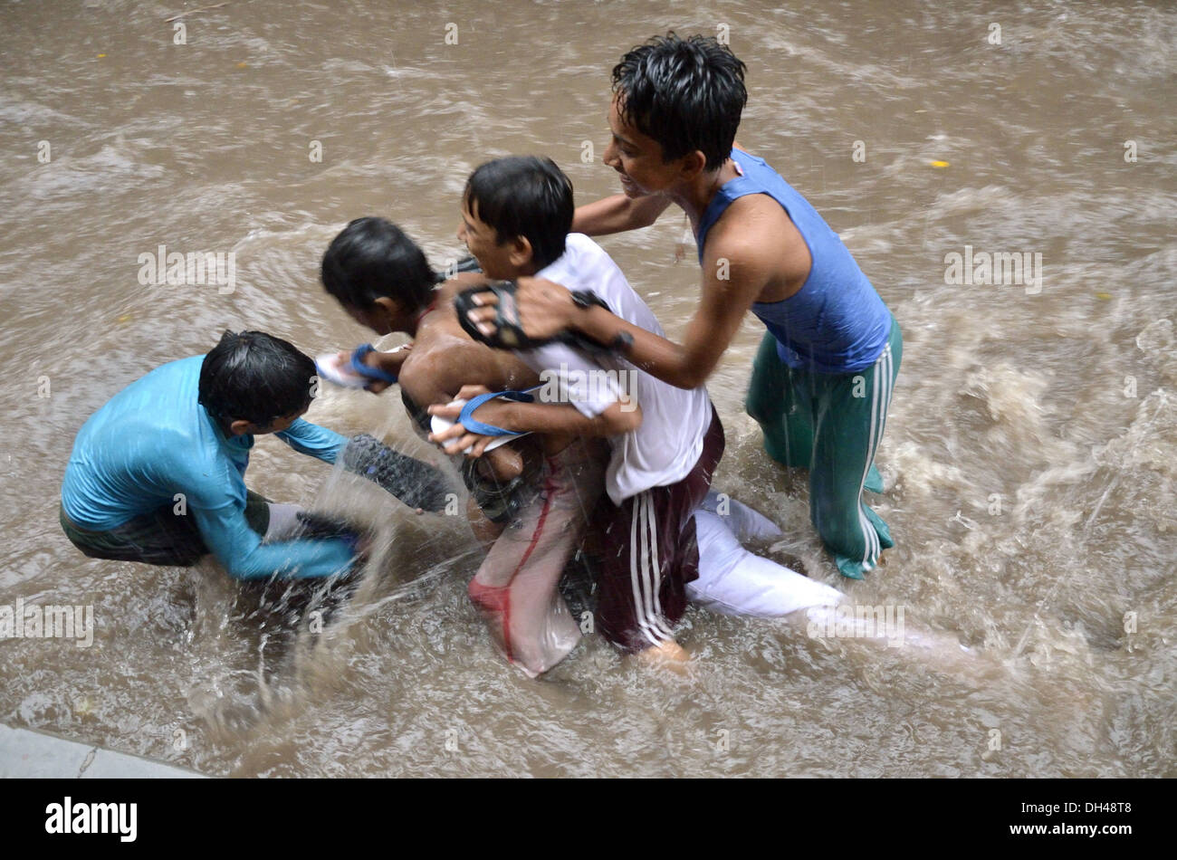 Ragazzi giocare in flusso di monsone di acqua di pioggia sulle strade di Jodhpur Rajasthan in India Foto Stock