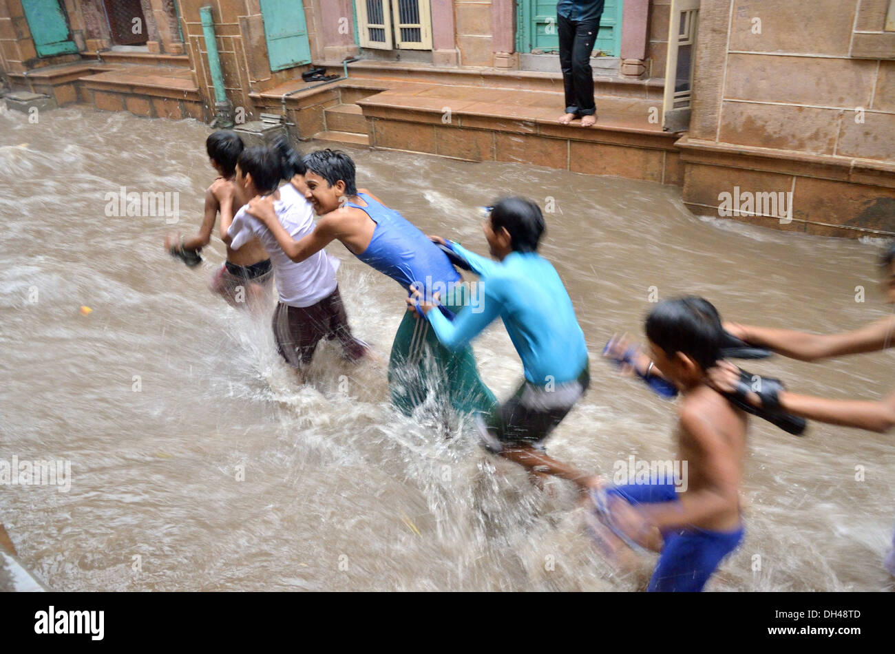 Ragazzi giocare in flusso di monsone di acqua di pioggia sulle strade di Jodhpur Rajasthan in India Foto Stock