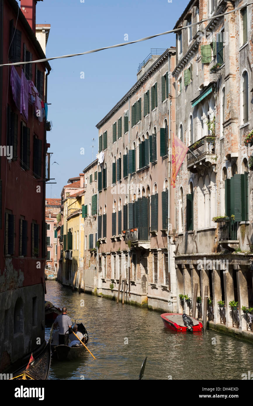 Piccola strada laterale a Venezia, Italia con gli uomini in una gondola. Foto Stock