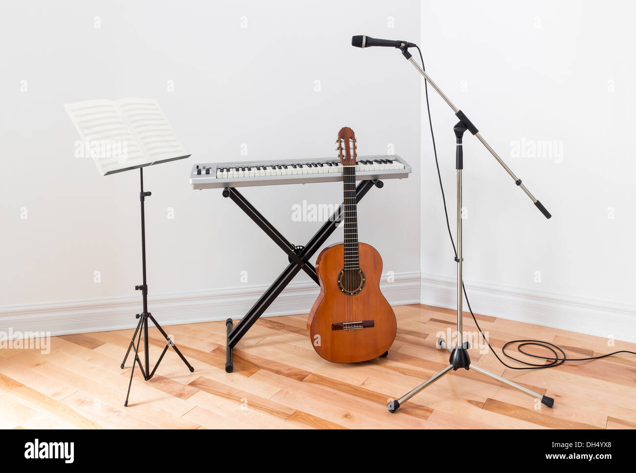 Strumenti musicali in una stanza. Piano elettrico, chitarra, microfono e stand con foglio di musica. Foto Stock
