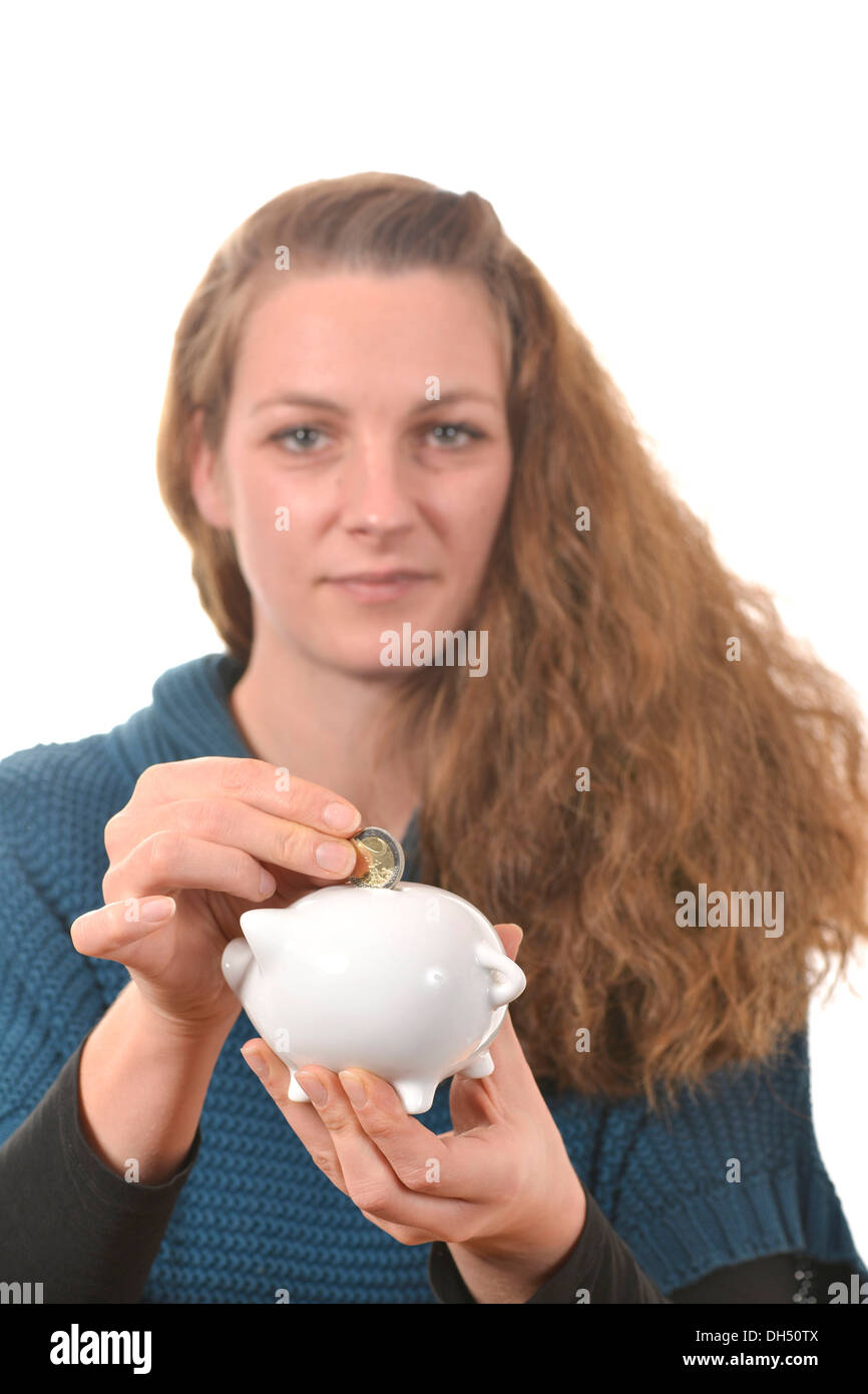 Donna mettendo a 2 euro monete in un salvadanaio Foto Stock