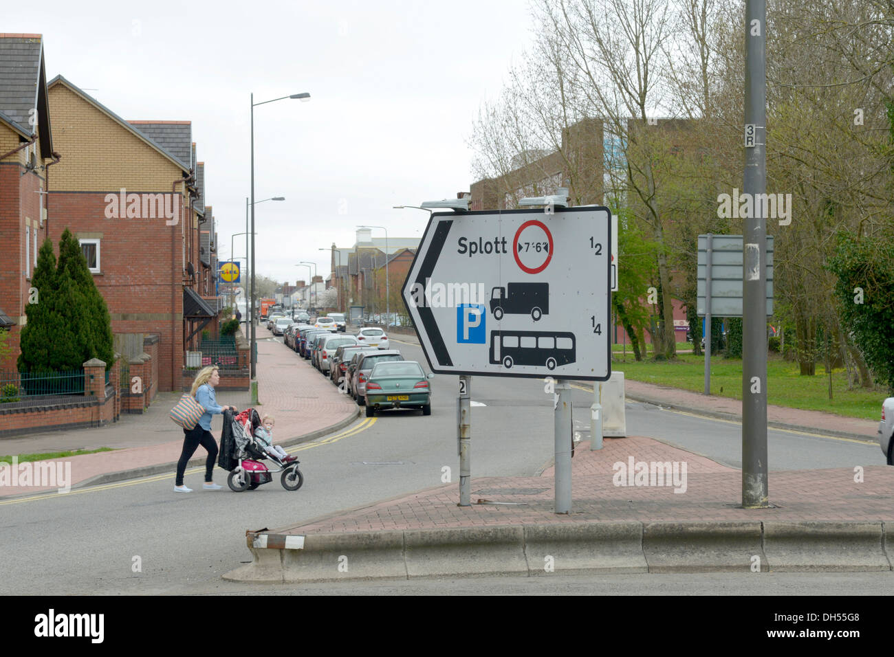 Giovane madre attraversamento Est Tyndall Street, con un cartello indicante il modo di Splott dal magic rotatoria a Cardiff Foto Stock