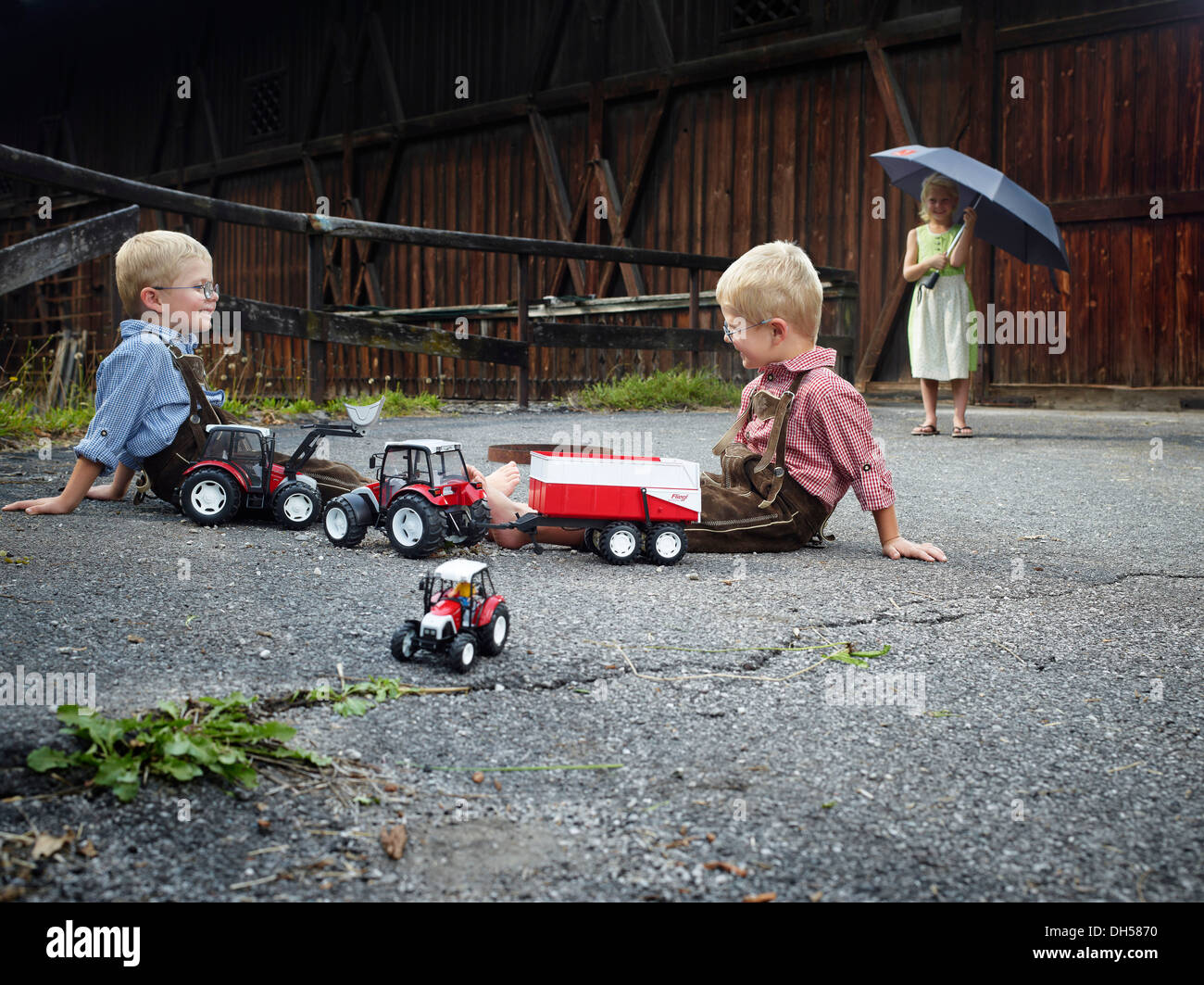 Bambini che giocano con i trattori giocattolo in agriturismo, Reith im Alpbachtal, Distretto di Kufstein, Nord Tirolo Tirolo, Austria Foto Stock