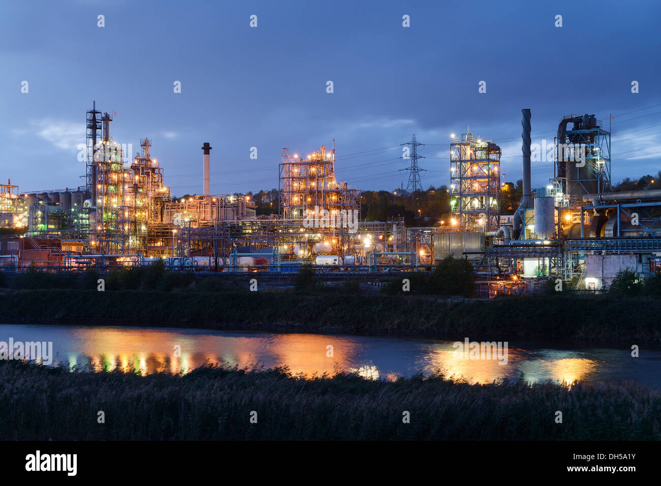Le luci della sera da parte di Ineos Chlor prodotto chimico industriale opere sul fiume Mersey estuario a Runcorn Cheshire Regno Unito Foto Stock