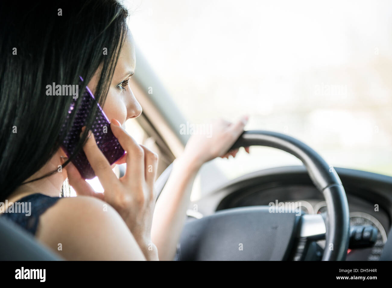 Giovane donna che chiama il telefono mentre si guida auto - Vista posteriore Foto Stock