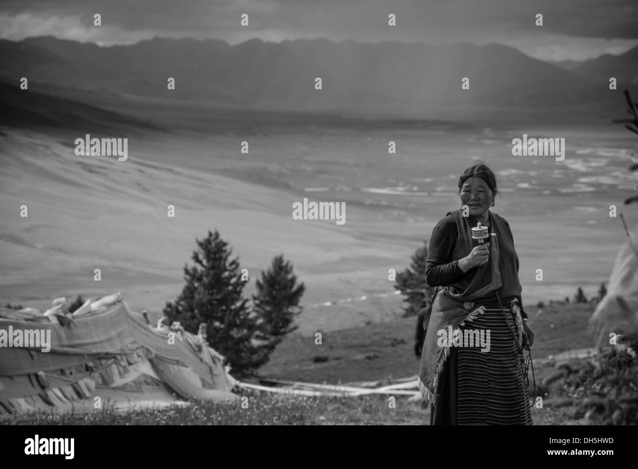 Una donna tibetana la filatura di una ruota di preghiera Foto Stock