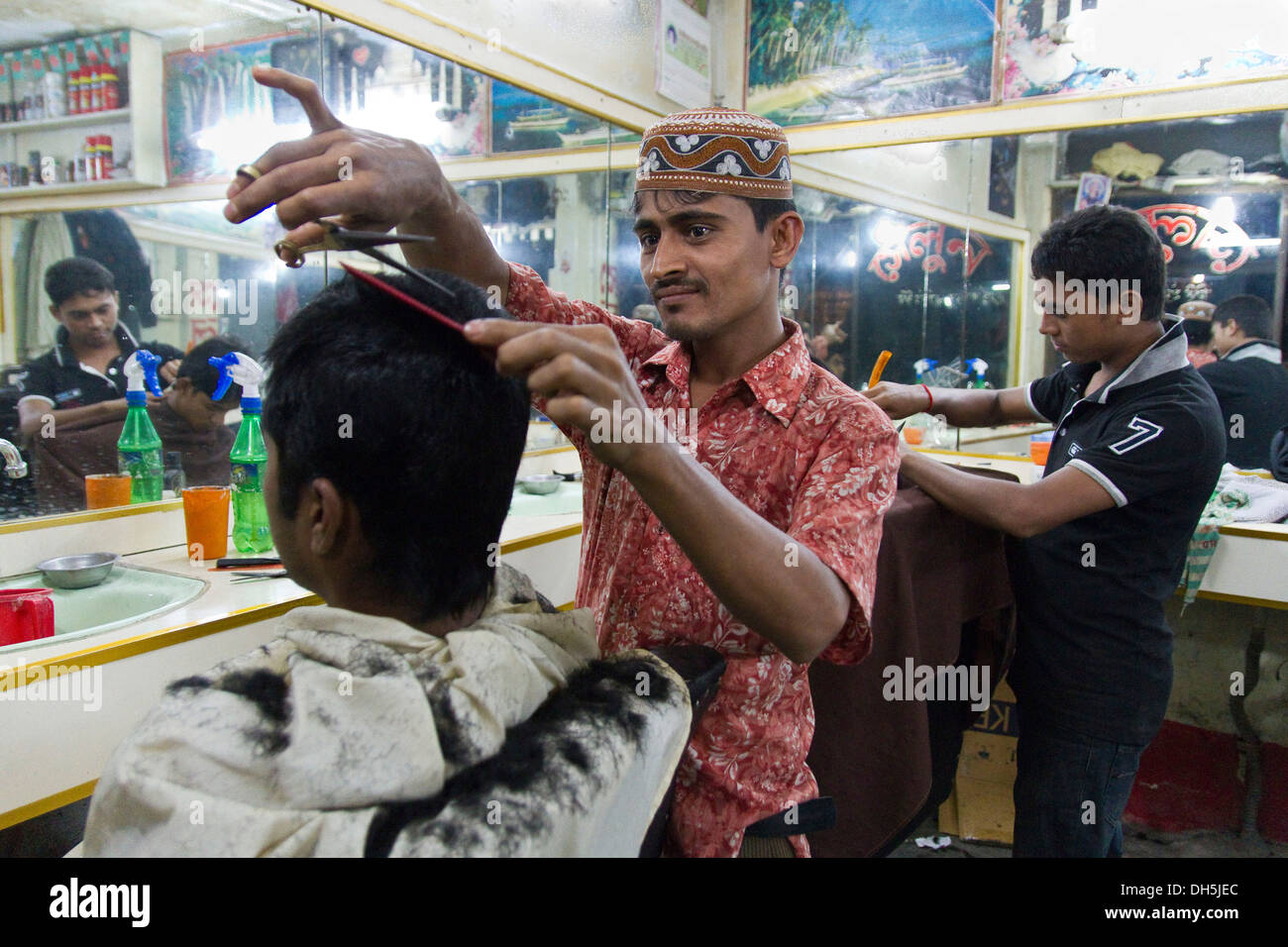 Due parrucchieri di tagliare il loro cliente ha i capelli, Nuovo Mercato, Dhaka, Bangladesh, Asia del Sud, Asia Foto Stock