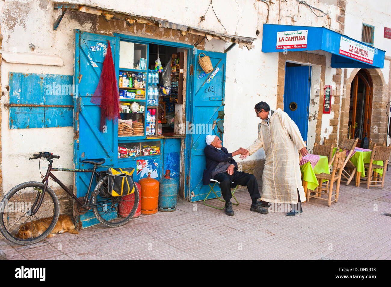 Due uomini saluto ogni altro di fronte a un piccolo negozio, Essaouira, Marocco, Africa Foto Stock