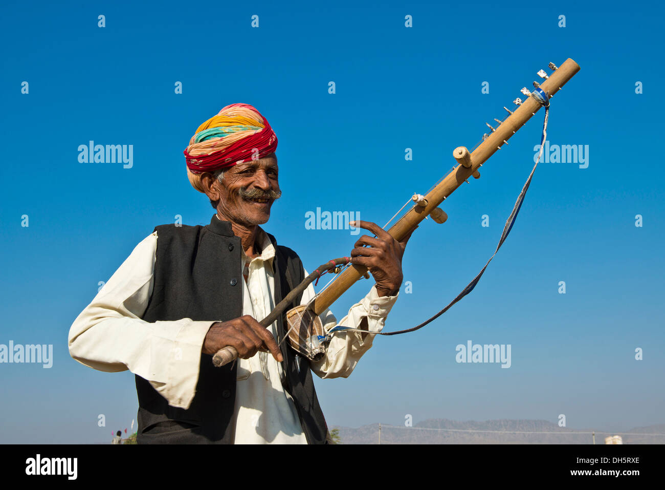 Anziani gentile uomo indiano, del Rajasthan, indossando un turbante colorato e giocando su un sitar, Kamelmarkt Pushkar, Pushkar Foto Stock