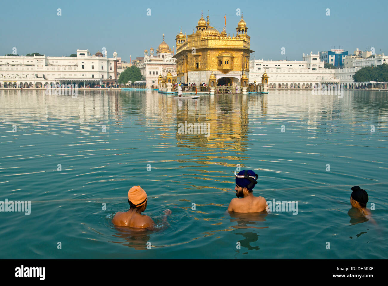 Tempio d'oro, Hari Mandir, il principale santuario della religione sikh, tre pellegrini indossa turbanti di prendere un bagno rituale nel lago santo di Foto Stock