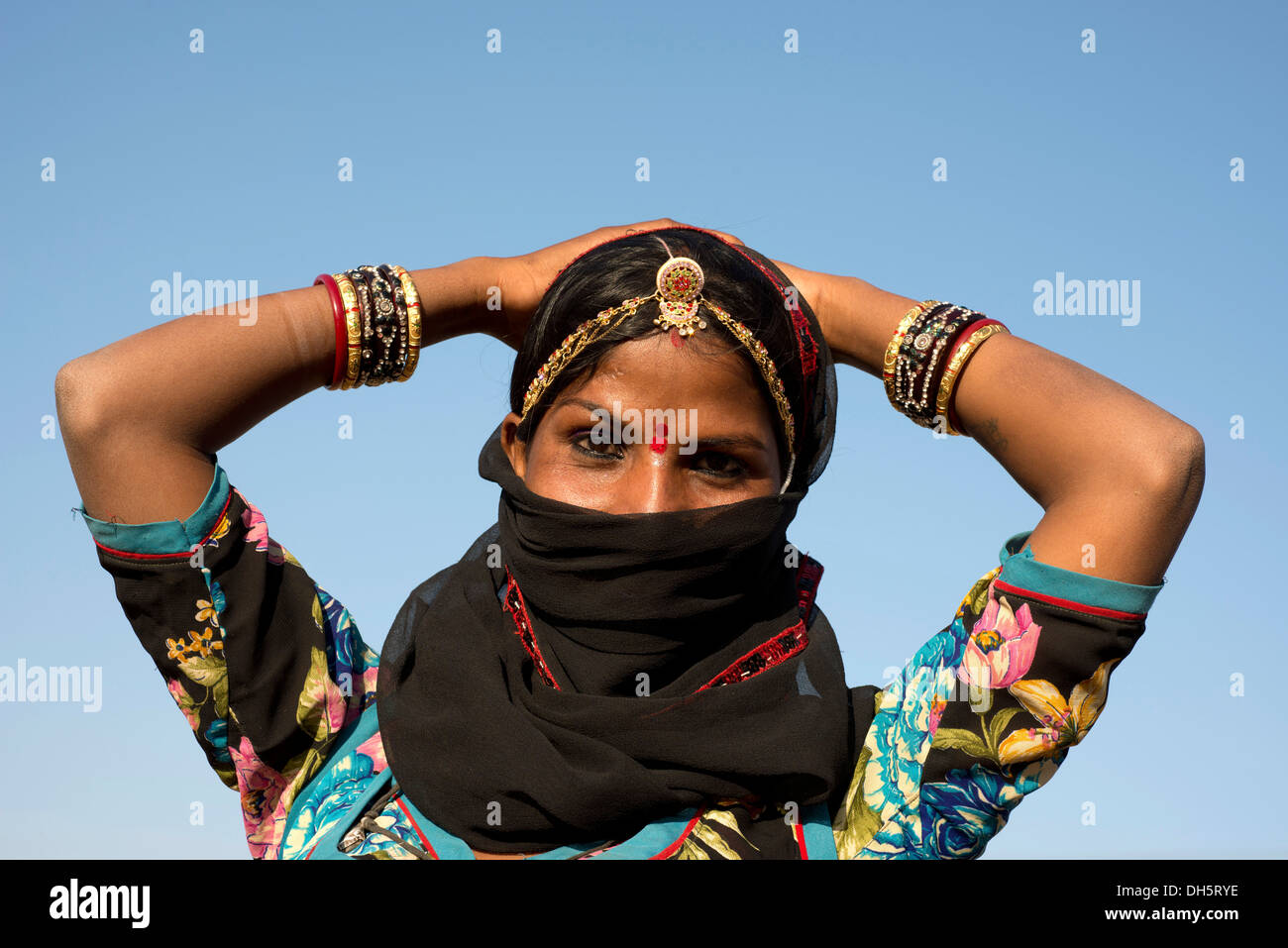 Giovane donna indiana con gioielli e una bindi che copre il volto con un velo nero, Pushkar, Rajasthan, India Foto Stock
