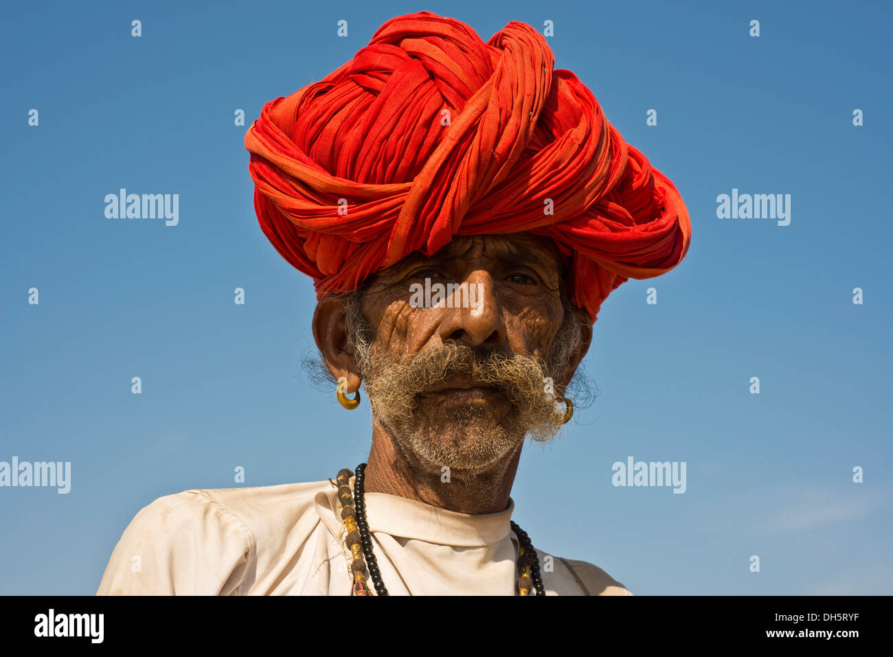 Uomo indiano con un turbante rosso e orecchini, ritratto, Pushkar, Rajasthan, India Foto Stock