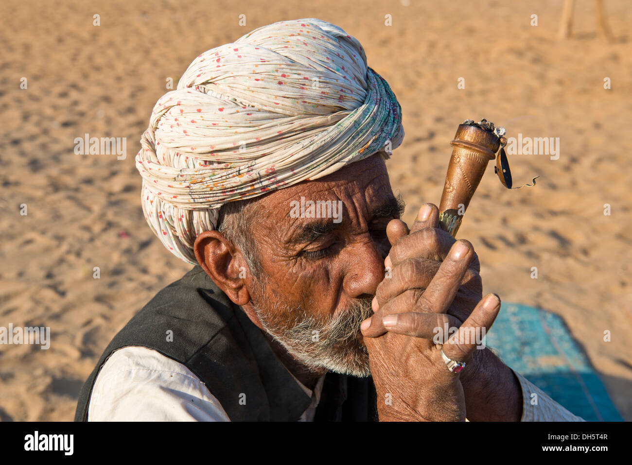 Uomo indiano con un turban fumare una tubazione di hash, Pushkar, Rajasthan, India Foto Stock