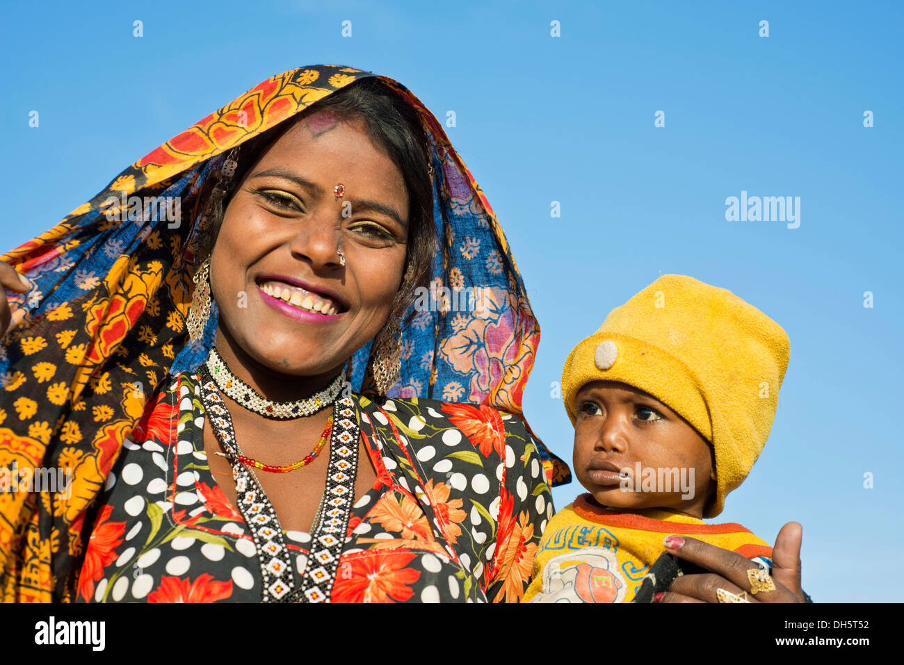 Sorridere le donne indiane con una sciarpa colorata tenendo un piccolo bambino in braccio, ritratto, Pushkar, Rajasthan, India Foto Stock