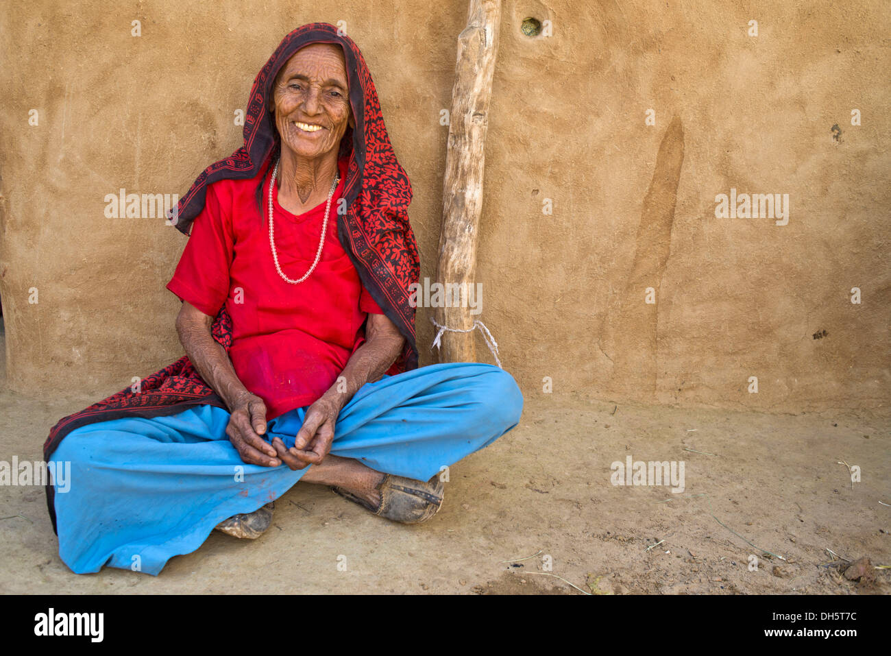 Il vecchio donna seduta sul terreno di fronte alla sua casa, Wüste Thar, Rajasthan, India Foto Stock