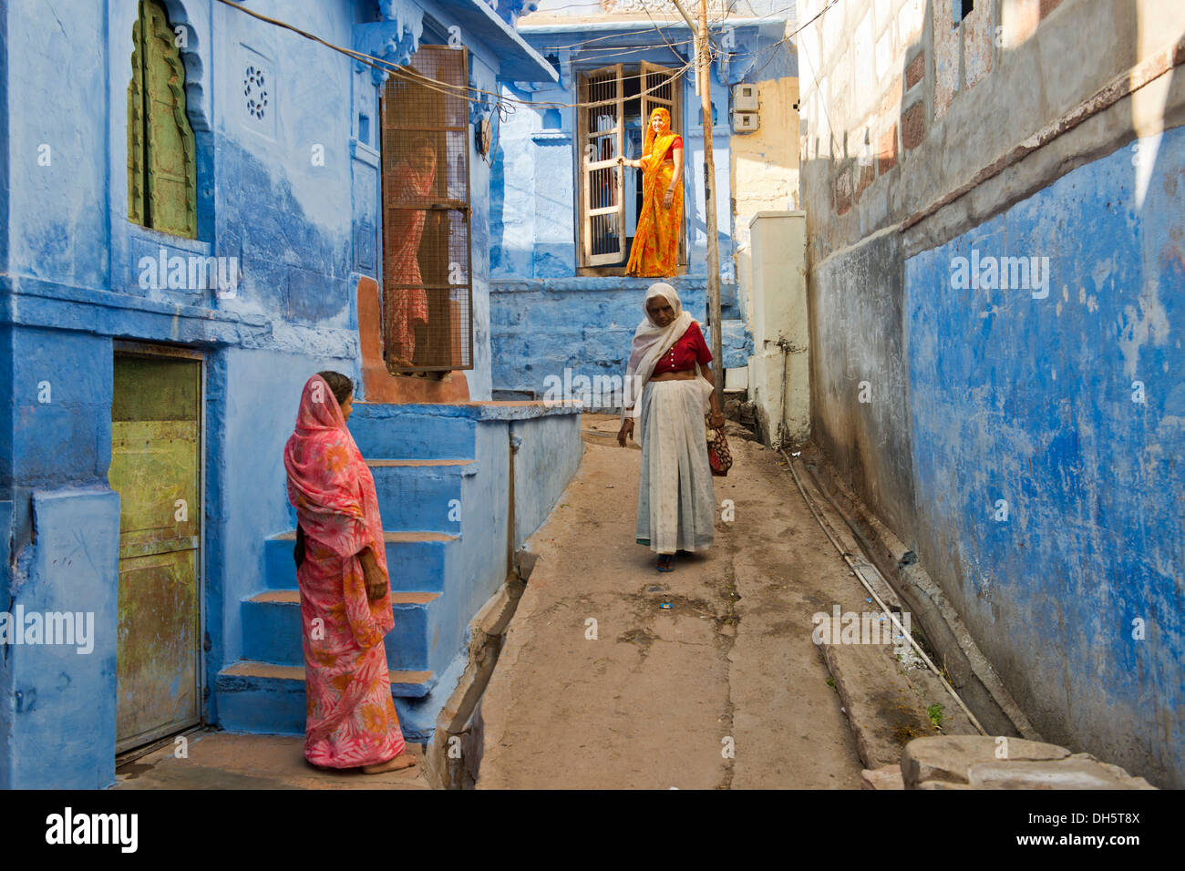 Quattro donne in sari tradizionale in un vicoletto con case blu, Brahmpuri, Jodhpur, Rajasthan, India Foto Stock
