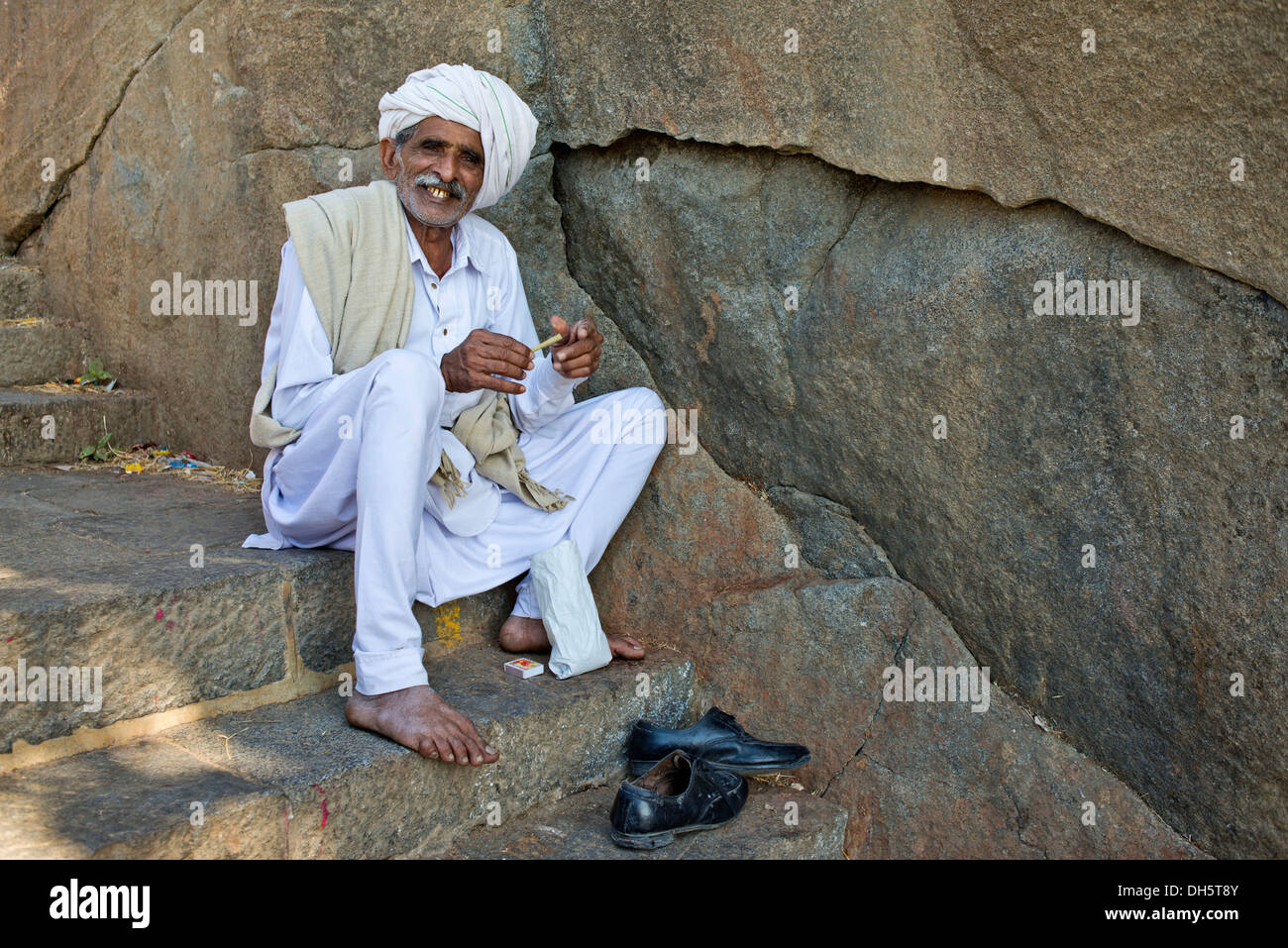 Un pellegrino vestito di bianco è seduto sulle scale che conducono al tempio sulla montagna sacra di Girnar, Junagadh, Gujarat Foto Stock