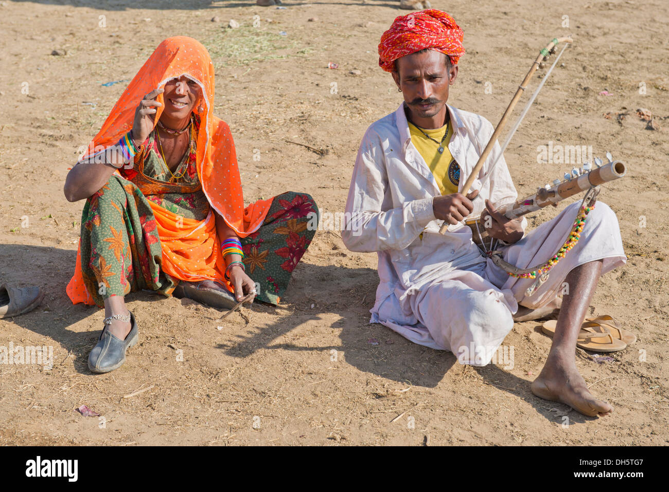 Indian gli uomini con un turbante e indossano il tradizionale maschile di indumento Dhoti, riproduzione di un sitar, una donna con il sari colorati seduta Foto Stock