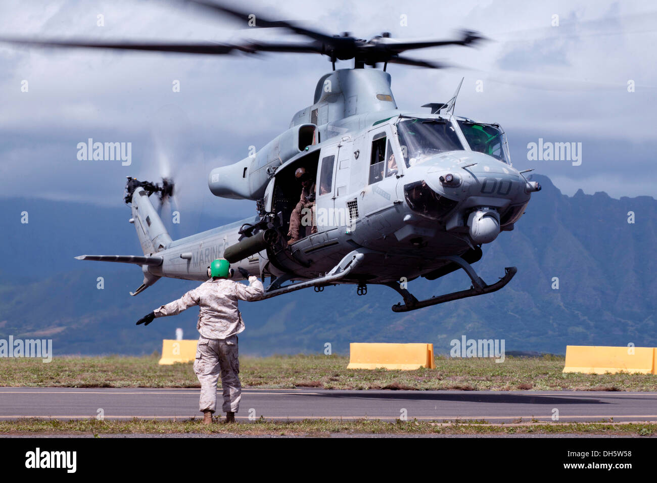 Stati Uniti Marine Corps Sergente Michea L. Potts con Marine supporto parafango distacco (MWSD) 24, fornisce segnali a mano al pilota di uscire UH-1Y Huey durante un esercizio demonstratinging MWSD-24s a doppio armamento in avanti e punto di rifornimento (FARP) funzionalità Foto Stock