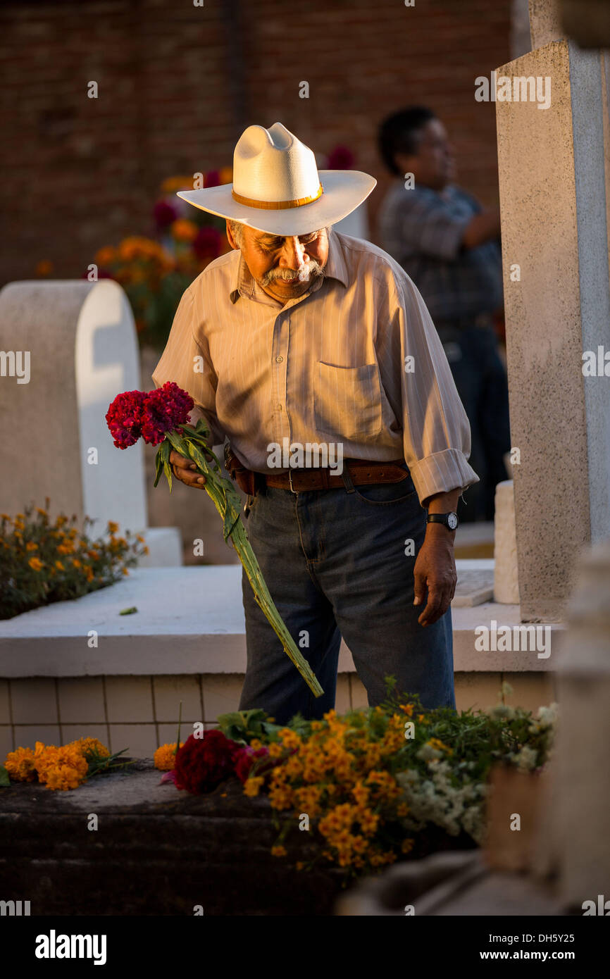 Un uomo anziano immissione dei fiori sulla tomba di sua moglie durante il giorno dei morti festival noto in spagnolo come d'un de Muertos al vecchio cimitero Ottobre 31, 2013 in Xoxocotlan, Messico. Foto Stock