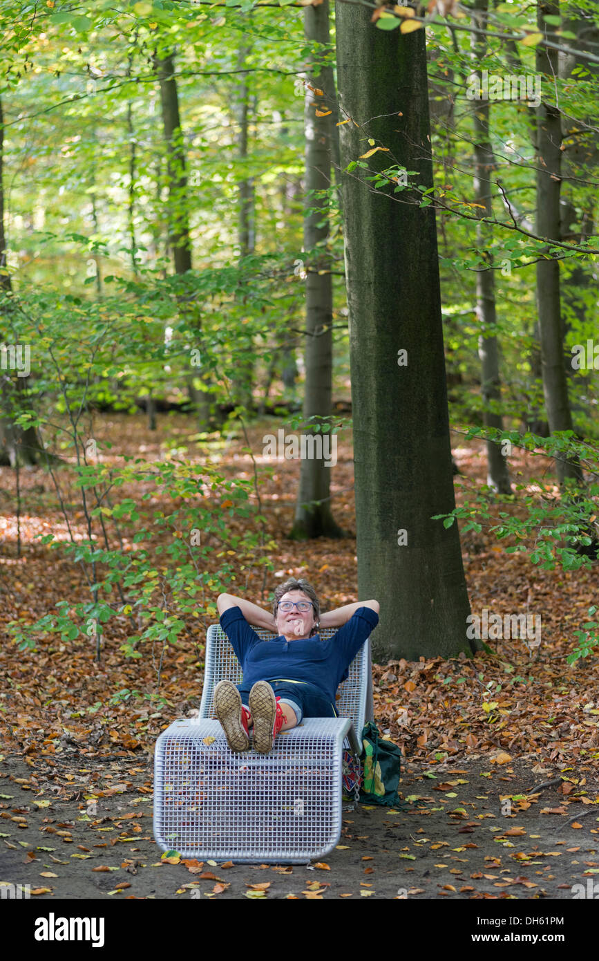 Donna relax nella foresta di autunno posa su una sedia Foto Stock