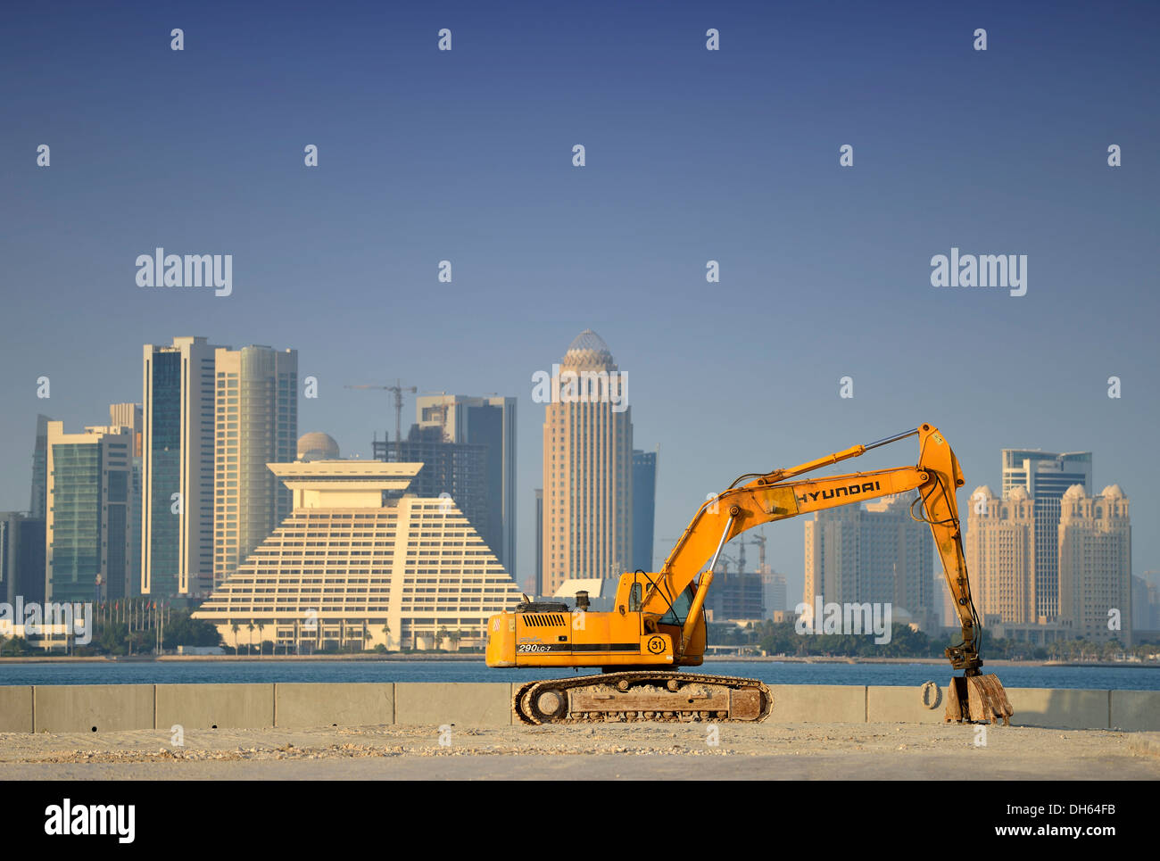 Boom edilizio a Doha, escavatore Hyundai di fronte allo skyline di Doha con Doha Sheraton Hotel Four Seasons Hotel Foto Stock
