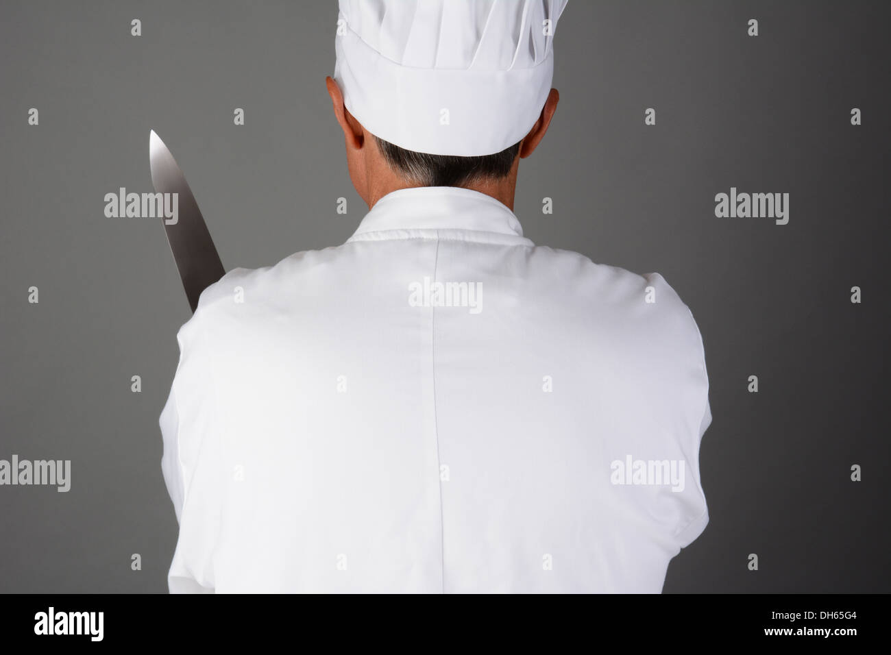 Primo piano di uno chef tenendo un coltello. L uomo è visto da dietro e è irriconoscibile. Foto Stock